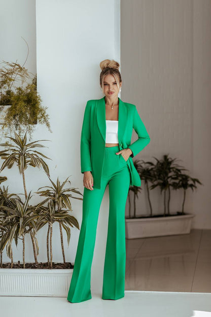 Woman in a green suit standing indoors with plants in the background