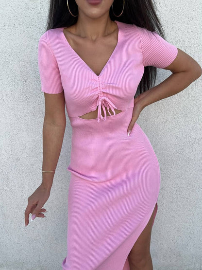 Woman wearing a pink ribbed dress with a cutout design on a light gray background
