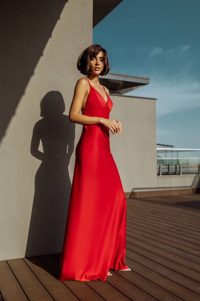 Woman in a red dress standing on a rooftop with a clear sky.