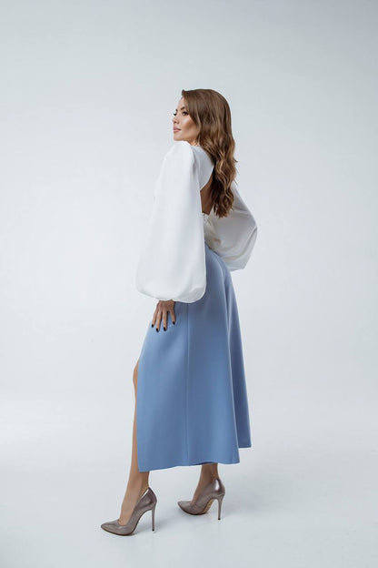 Woman wearing a white blouse and blue skirt on a light gray background