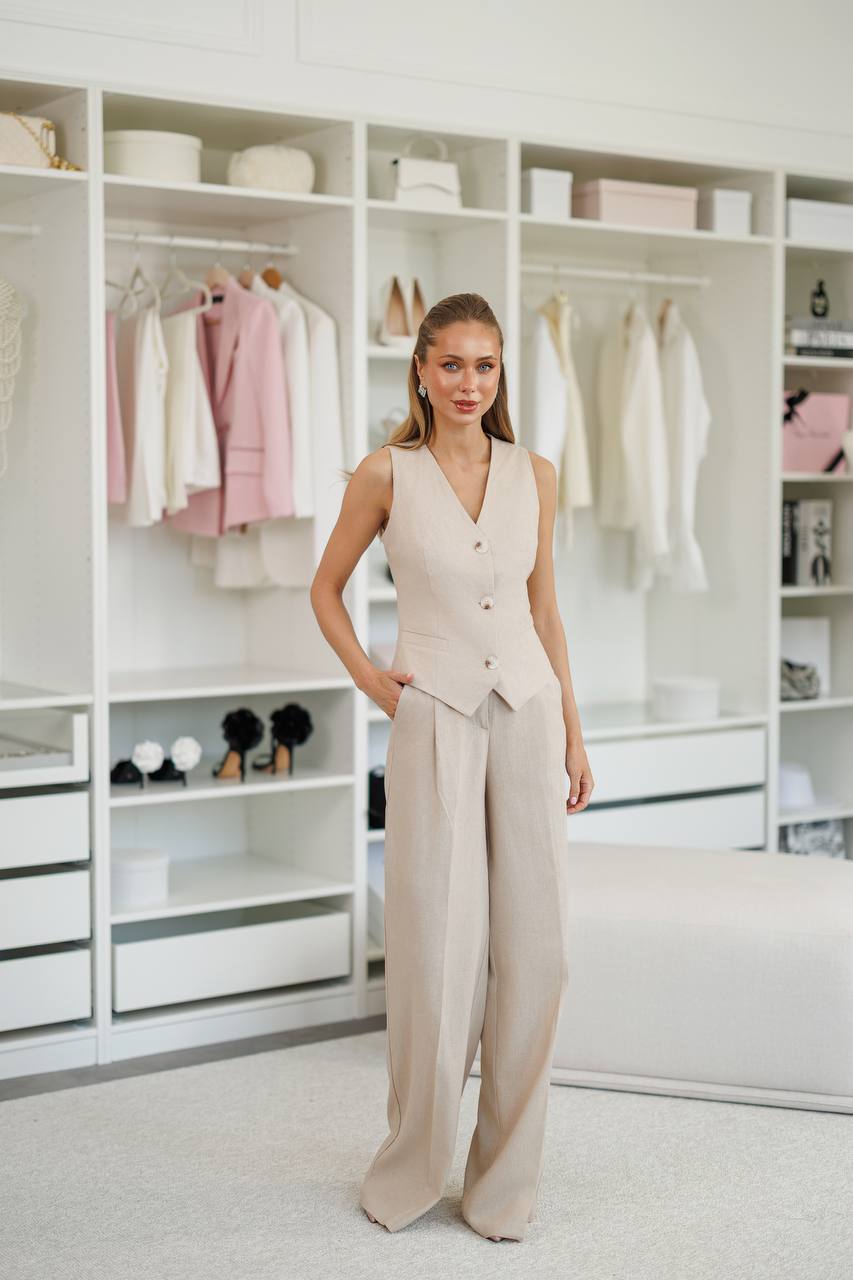 Woman in a beige outfit standing in a well-organized wardrobe.
