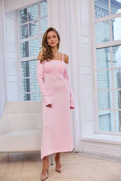 Woman in a pink dress standing in a bright room with large windows.