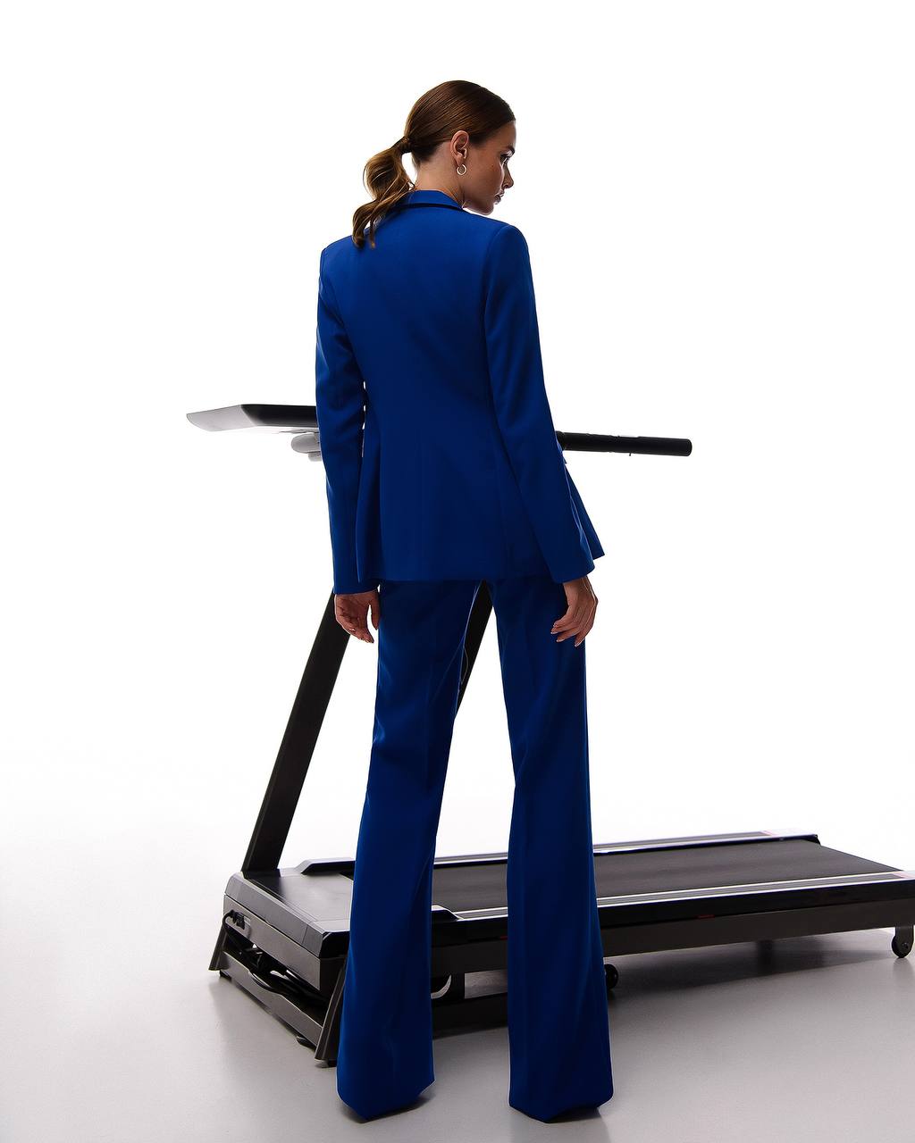 Person wearing a blue suit standing on a treadmill against a white background