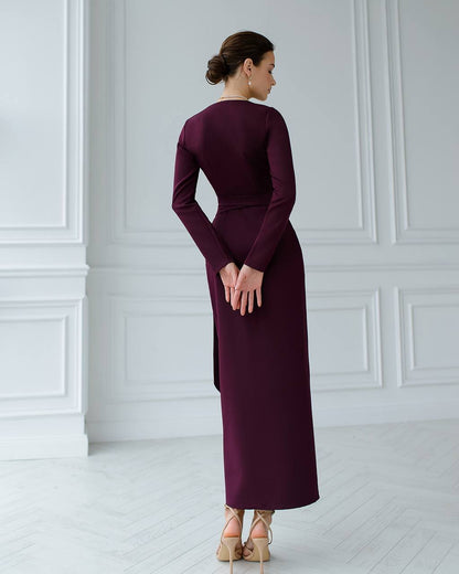 Woman wearing a long burgundy dress in a room with white walls and floor.