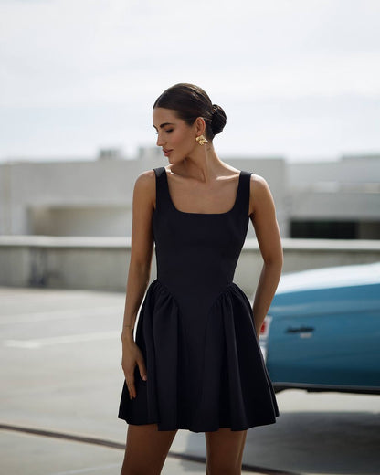 Woman wearing a black dress standing outdoors with a blurred background