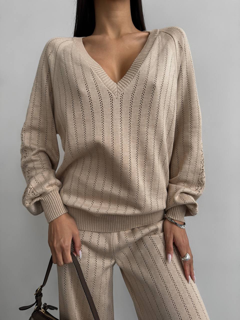 Beige knitted sweater and pants set on a plain background