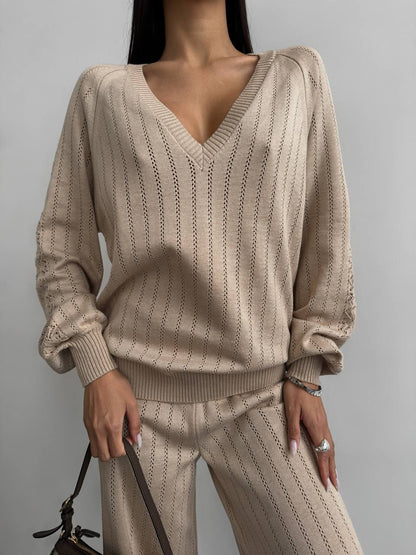 Beige knitted sweater and pants set on a plain background