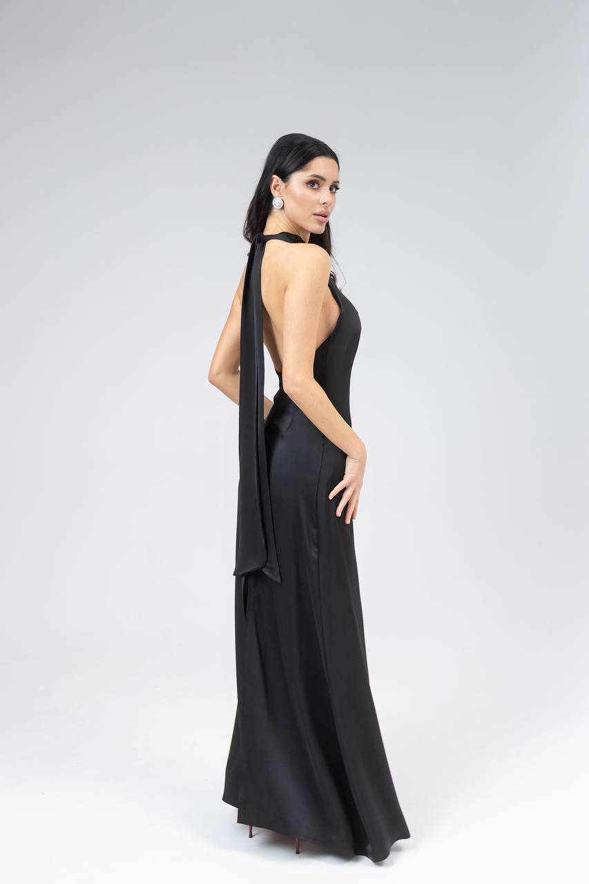 Woman wearing a black evening gown with a draped effect on a white background