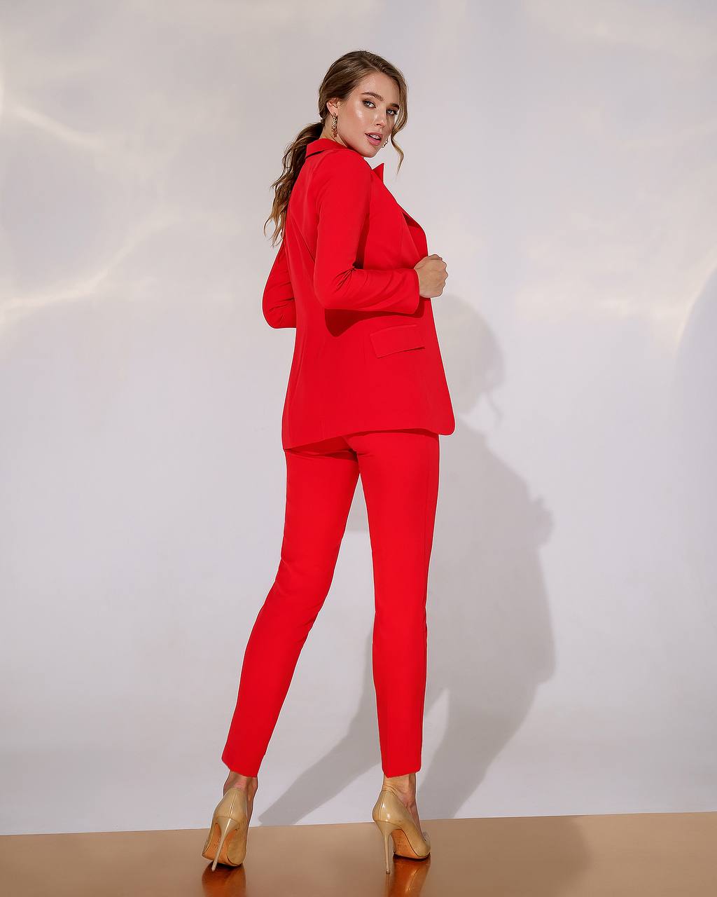 Woman wearing a red suit with gold shoes on a white background