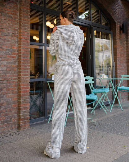 Person wearing a checkered outfit standing outside a building with tables and chairs.