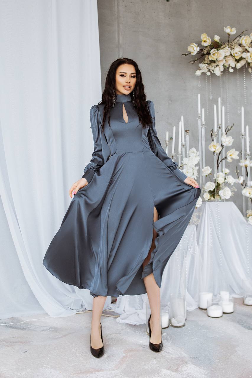 Woman in a gray dress standing in a decorated room with white flowers and candles.