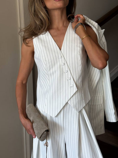 Woman wearing a white pinstripe suit with a beige jacket.