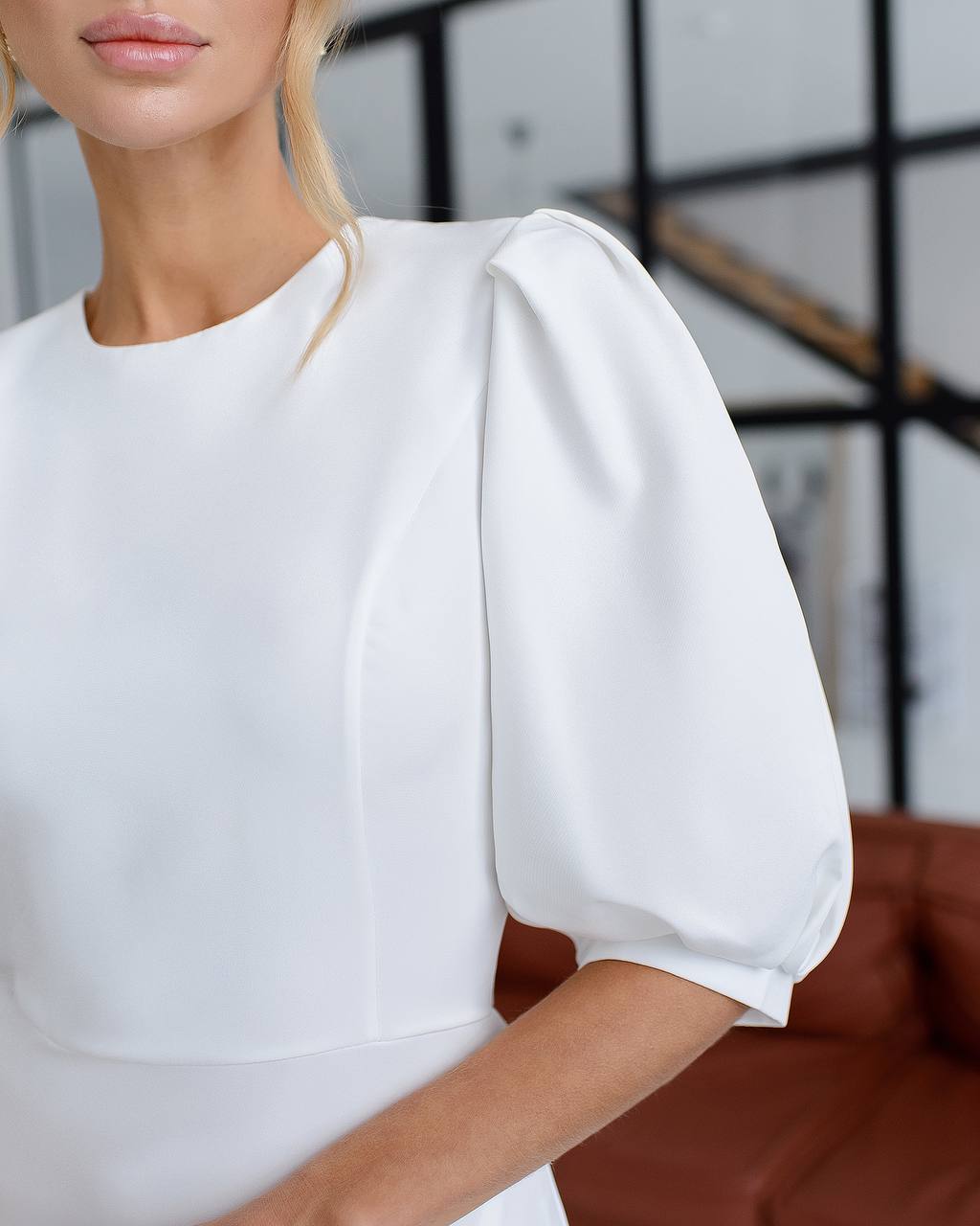 White dress with puff sleeves worn by a person, blurred background