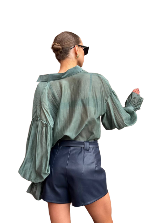 Person wearing a green blouse and navy shorts on a white background