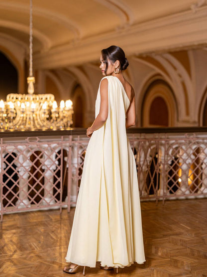 Woman in a white dress standing in an elegant interior setting with chandeliers.