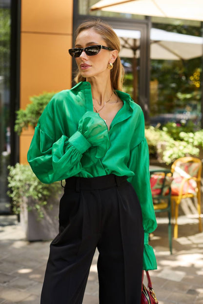 Woman wearing a green shirt and black pants outdoors.