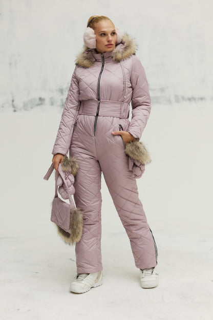 Person wearing a pink snowsuit with fur accents in a snowy landscape