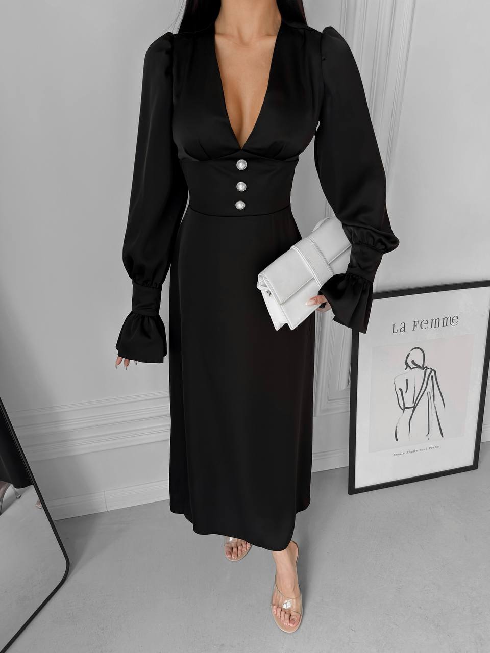 Woman wearing a black dress with long sleeves in an indoor setting.