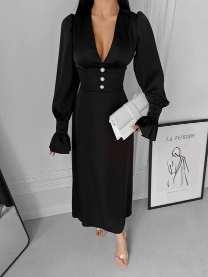 Woman wearing a black dress with long sleeves in an indoor setting.