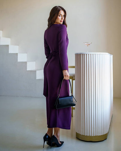 Woman in a purple dress standing in a modern interior setting with a white cylindrical object.