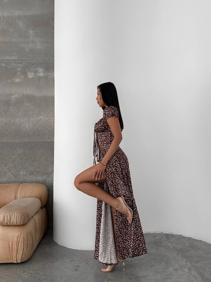 Woman in a patterned dress standing against a white wall with a beige sofa.