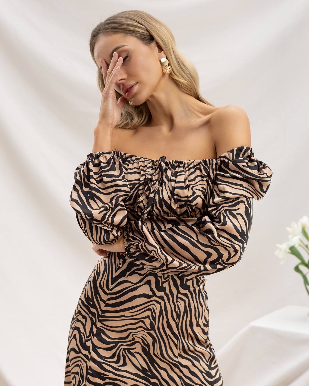 Woman wearing a zebra print off-shoulder dress against a neutral background