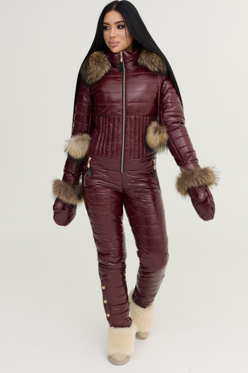 Person wearing a burgundy quilted jumpsuit with fur trim on a white background