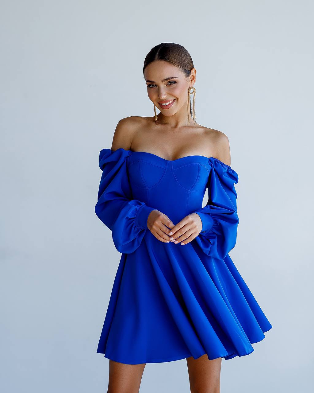 Woman wearing a blue off-shoulder dress against a plain background