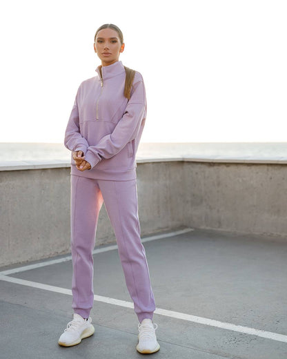 Person wearing a light purple tracksuit standing on a rooftop.