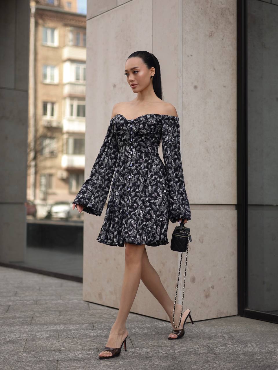 Woman in a floral off-shoulder dress walking on a city street.