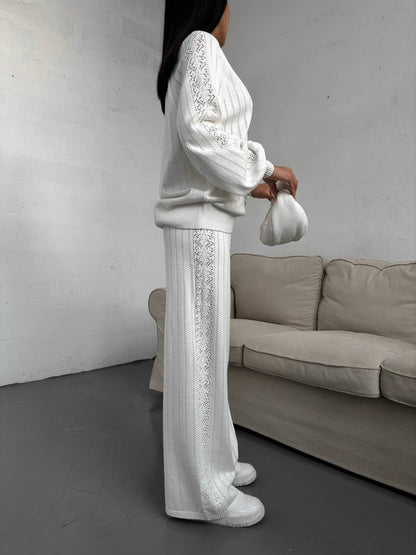 Person wearing a white outfit with lace details in a minimalistic room.