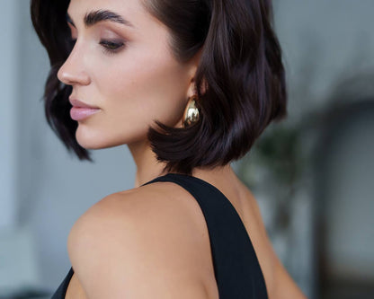 Woman with styled hair and earrings against a blurred background