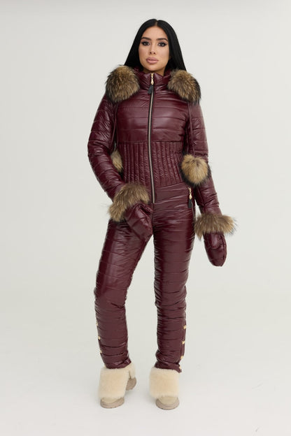 Person wearing a burgundy quilted jumpsuit with fur trim on a white background