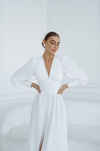 Woman wearing a white dress with long sleeves against a white background