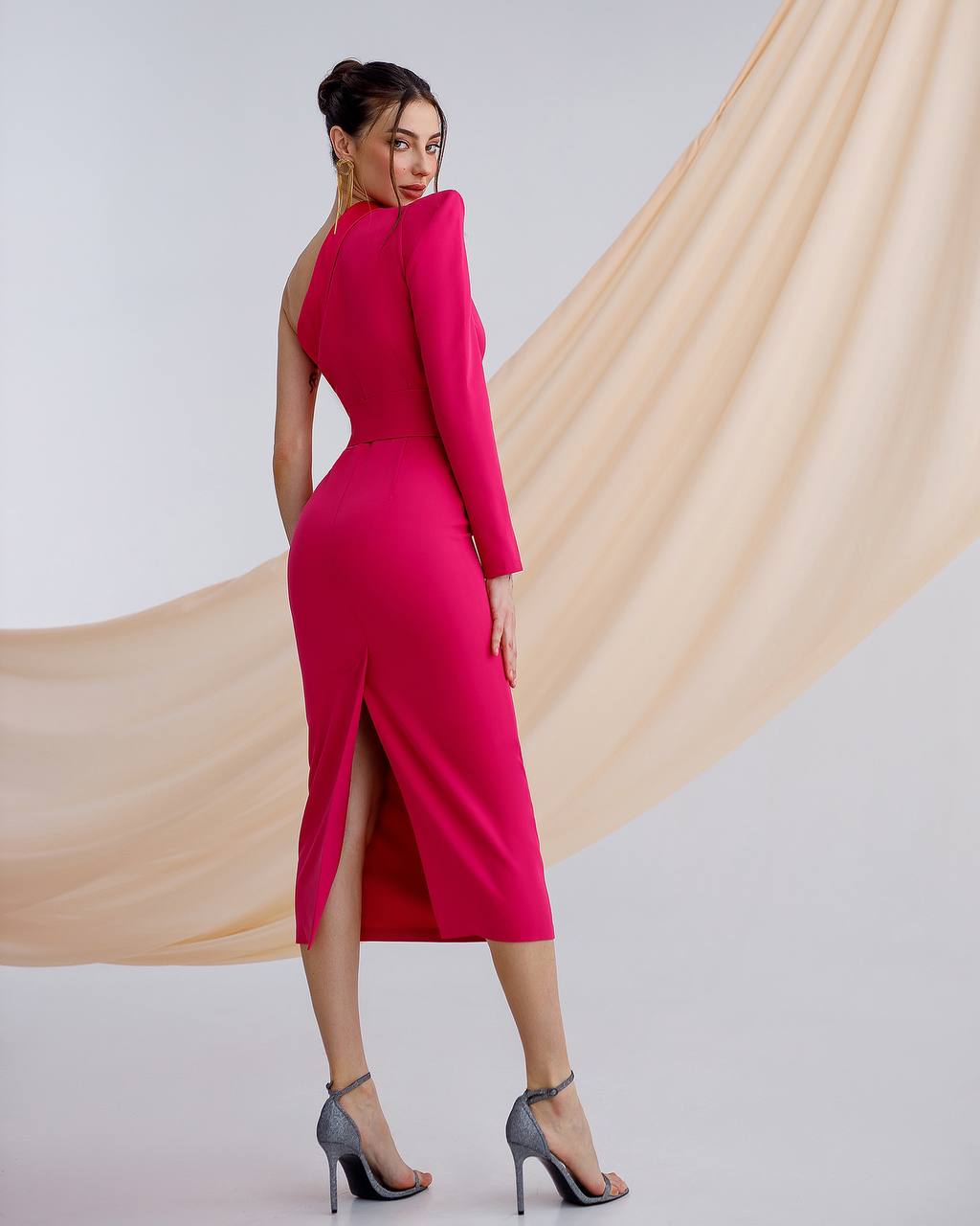Woman wearing a pink dress with a beige curtain in the background