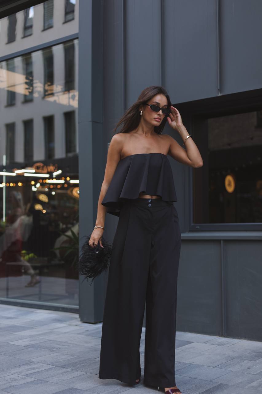 Woman in a black outfit standing outdoors near a building