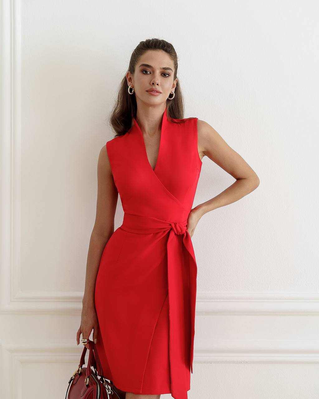 Woman wearing a red dress against a white wall