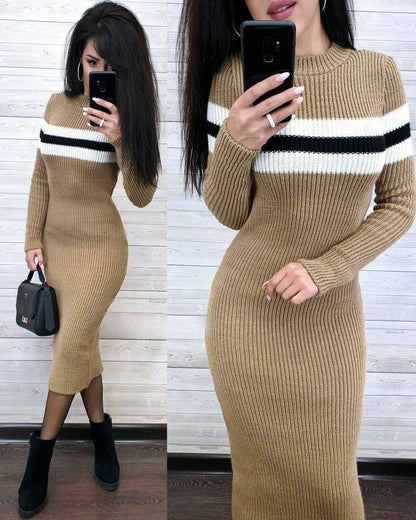 Woman wearing a beige sweater dress with black and white stripes, holding a phone.