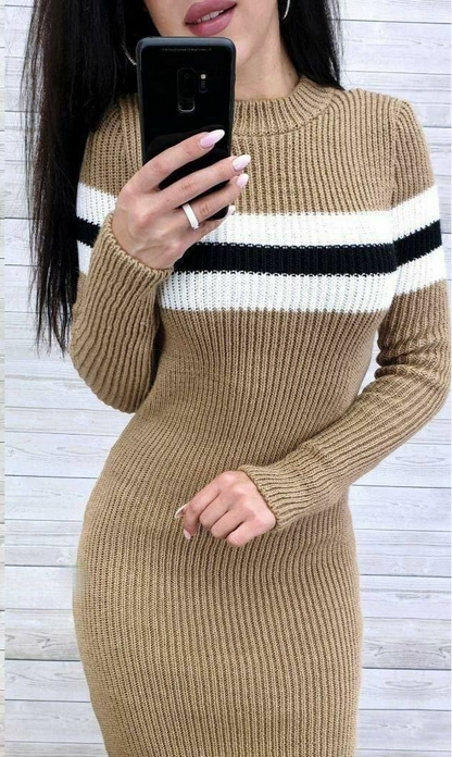 Person wearing a beige ribbed sweater dress with black and white stripes, holding a phone.