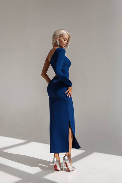 Woman in a blue dress standing against a plain background