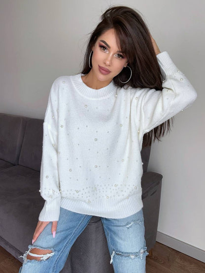 Woman wearing a light blue sweater and ripped jeans indoors.
