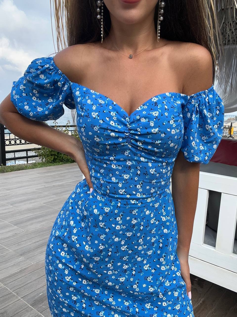 Woman wearing a blue floral dress with puffed sleeves outdoors.
