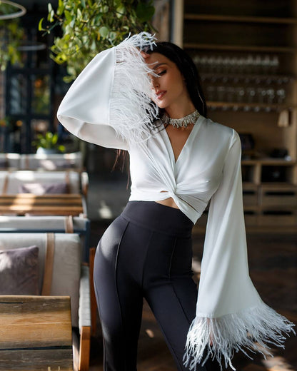 Woman wearing a white blouse with fringe and black leggings in an indoor setting.