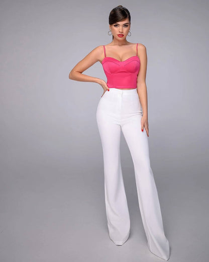 Woman wearing a pink top and white pants on a gray background