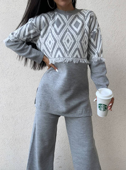 Person wearing a gray and white patterned sweater and matching pants, holding a Starbucks cup.