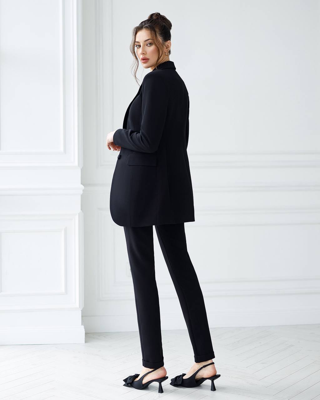 Woman wearing a black suit standing against a white background
