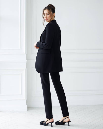 Woman wearing a black suit standing against a white background