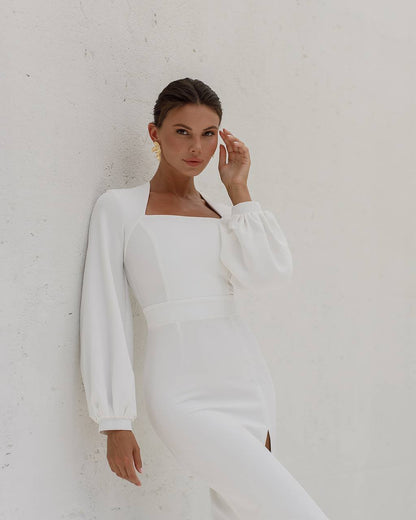 Woman wearing a white long-sleeve dress against a plain background