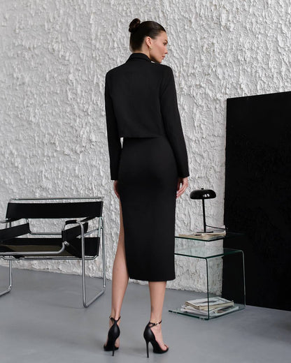 Woman in a black outfit standing in a modern room with minimal decor.