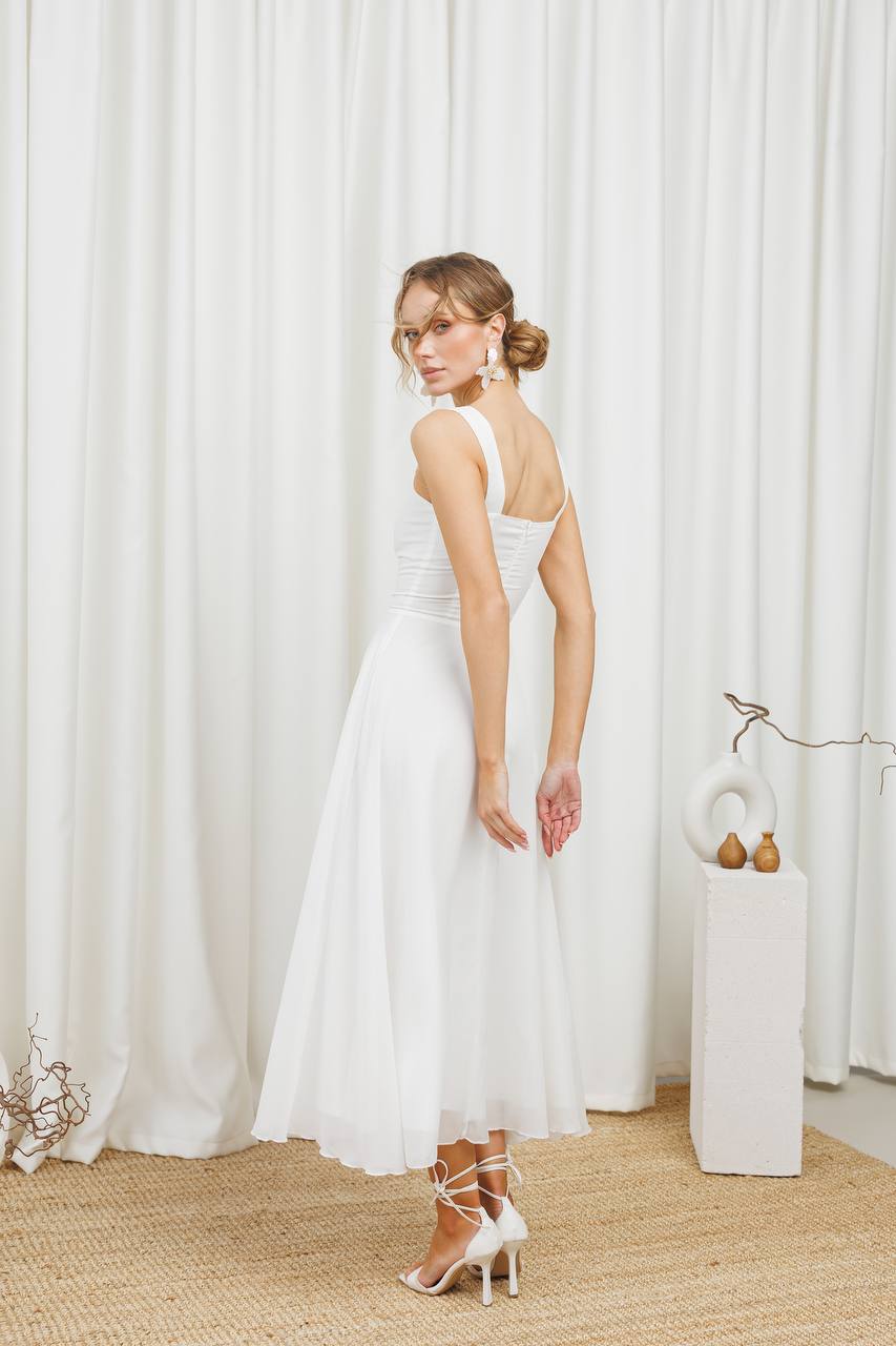 Woman in a white dress standing in front of white curtains